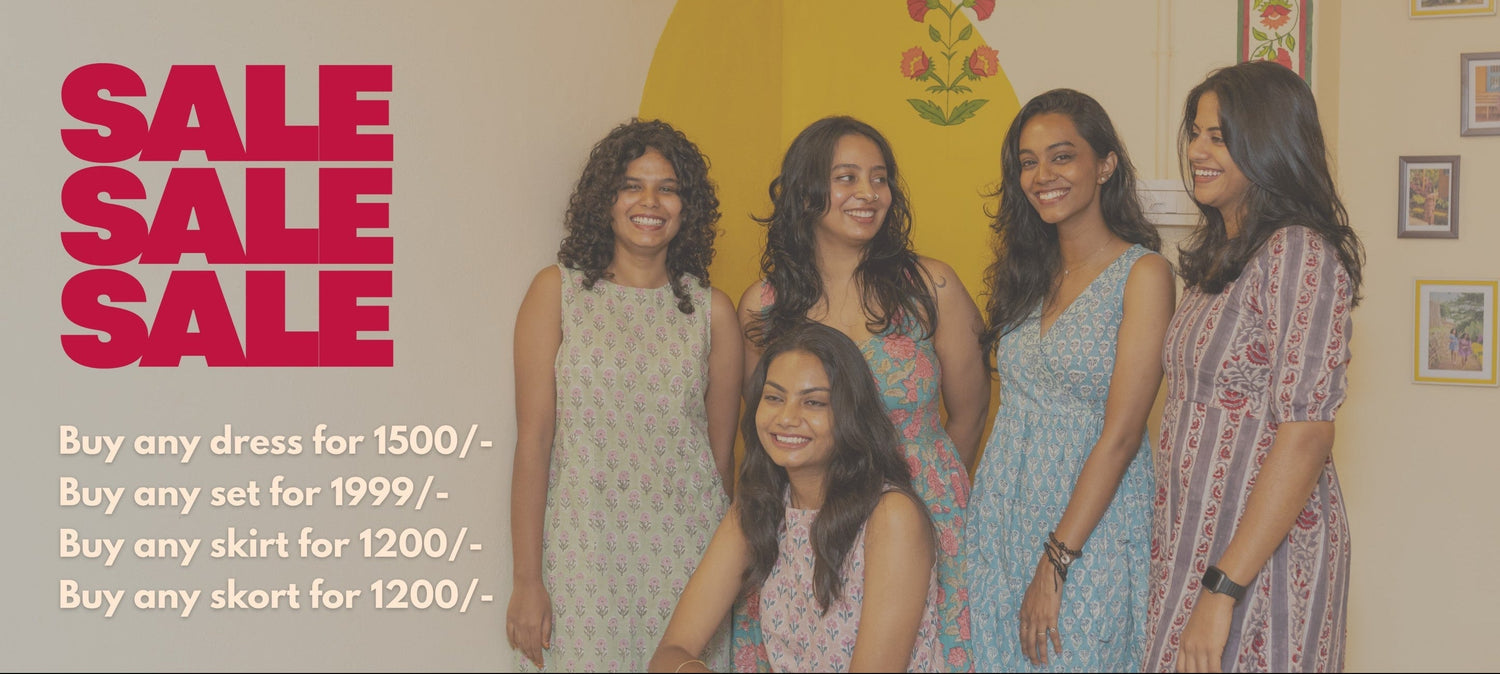 Group of women posing in front of a sale advertisement with text on a wall.